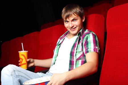 Young man sitting in cinema and watching movieの写真素材