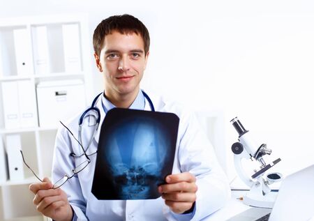 Young confident and friendly doctor in medical officeの写真素材