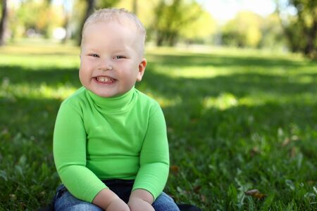 Happy little boy having fun in green summer parkの写真素材