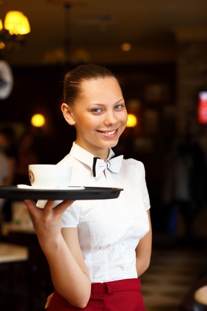 Portrait of young waitress in white blouse holding a trayの写真素材