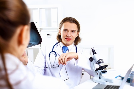 Young confident and friendly doctor in medical officeの写真素材