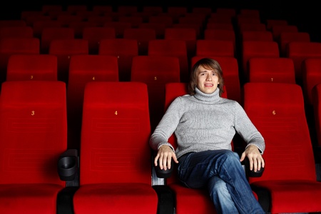 Young man sitting in cinema and watching movieの写真素材