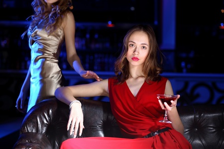 Young woman in evening dress in night club with a drinkの写真素材