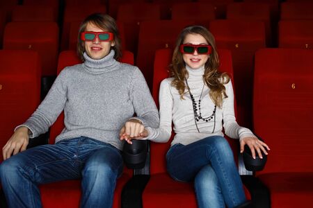 Young couple sitting in cinema and watching movieの写真素材