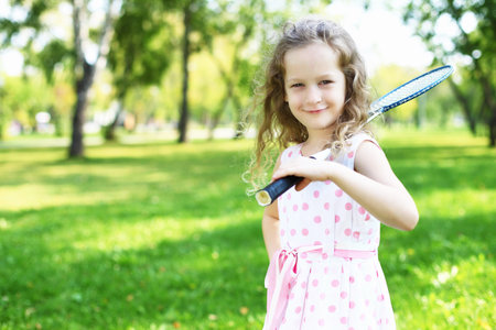 Little happy girl having fun in green summer parkの写真素材