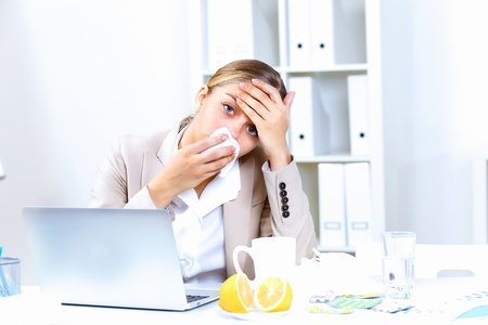 Young woman feeling unwell and sick in officeの写真素材