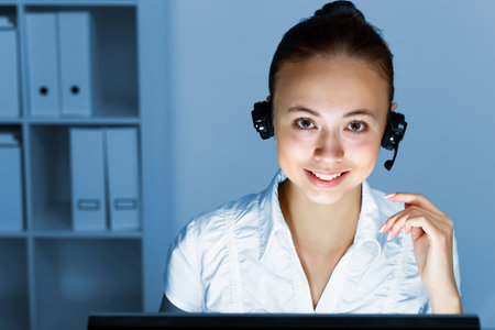 Young woman in business wear in headset working with computer