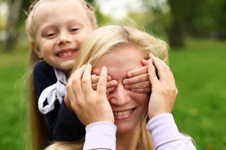 Young mother playing with little daughter in green summer parkの写真素材