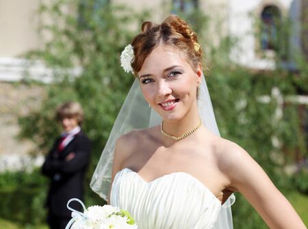 Portrait of a young bride in a white dress with a bouquet of flowers.の写真素材