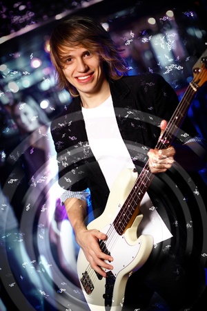 Young guitar player with instrument performing in night clubの写真素材