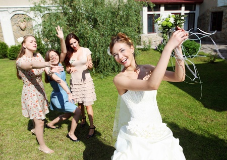 Young bride in white wedding dress throws a bouquet of flowers to bridesmaidsの写真素材