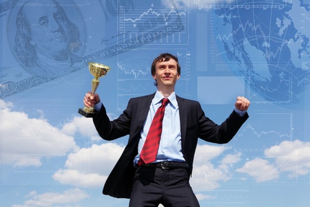 young businessman in a suit with a golden cup against blue skyの写真素材