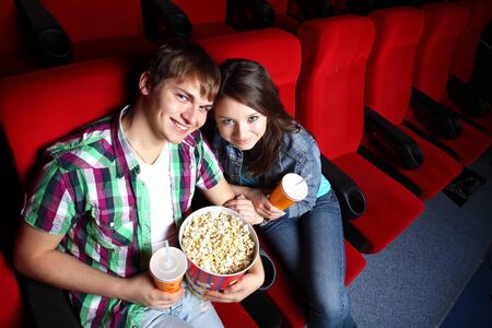 Young couple sitting in cinema and watching movieの写真素材