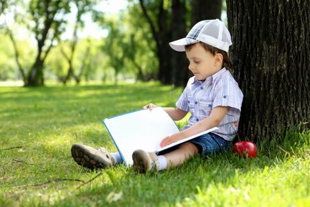 Portrait of a boy sitting with a book in the parkの写真素材
