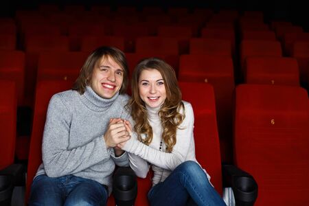 Young couple sitting in cinema and watching movieの写真素材