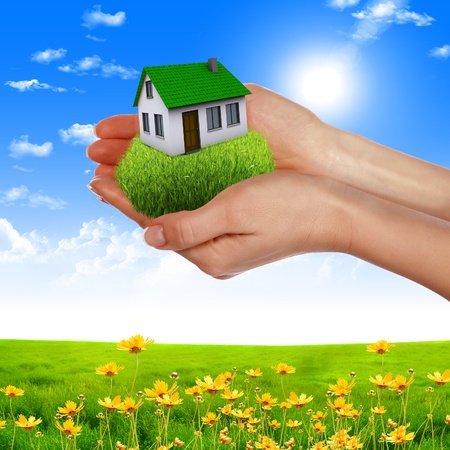 human hands holding model of a house against nature backgroundの写真素材