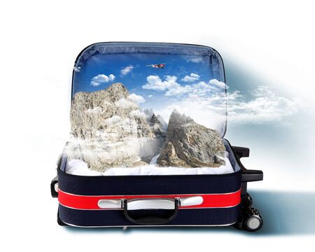 Red suitcase with mountains covered with snow insideの写真素材