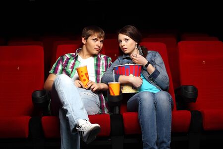 Young couple sitting in cinema and watching movieの写真素材