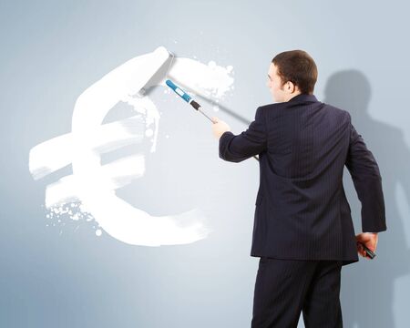 Young man with paint brush and banknote painted on the wallの写真素材