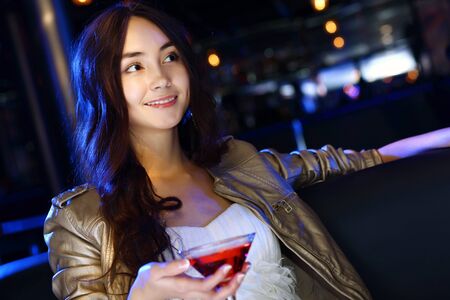 Portrait of young attractive woman in night club with a drinkの写真素材