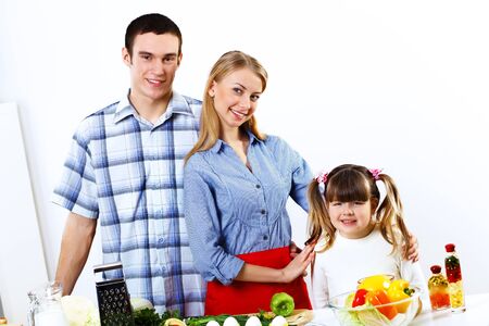 Happy young family with a daughter cooking together at homeの写真素材