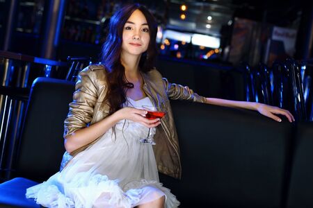 Portrait of young attractive woman in night club with a drinkの写真素材