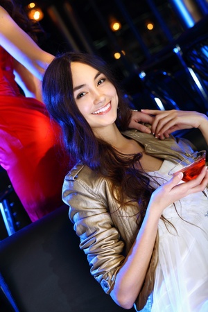 Portrait of young attractive woman in night club with a drinkの写真素材