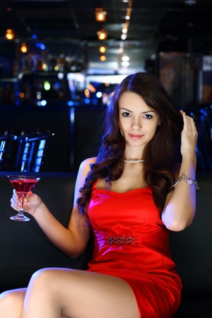 Portrait of young attractive woman in night club with a drinkの写真素材