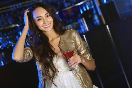 Portrait of young attractive woman in night club with a drinkの写真素材