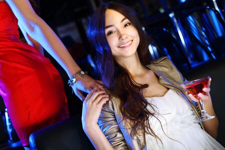 Portrait of young attractive woman in night club with a drinkの写真素材