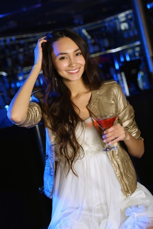 Portrait of young attractive woman in night club with a drinkの写真素材
