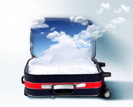 Red suitcase with mountains covered with snow insideの写真素材