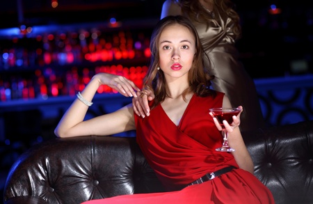 Young woman in evening dress in night club with a drinkの写真素材