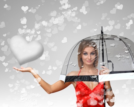 Pretty young woman with umbrella and with hearts on the backgroundの写真素材