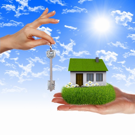 Human hand against blue sky background and houseの写真素材