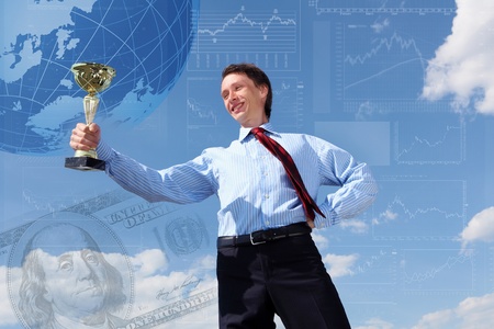 young businessman in a suit with a golden cup against blue skyの写真素材