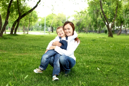 Mother with her son sitting on the grass  in the summer parkの写真素材
