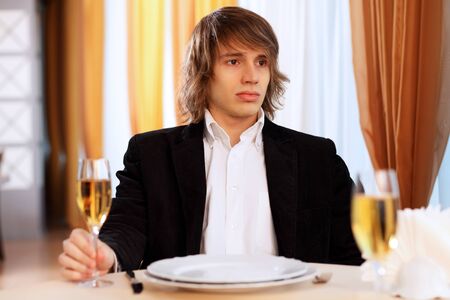 Portrait of a young handsome man sitting in restaurantの写真素材