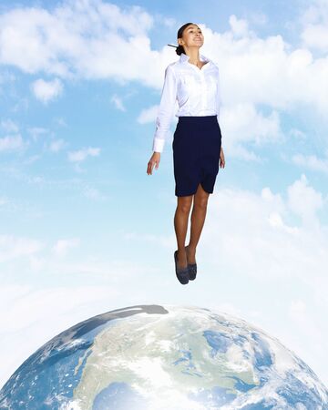 Young woman jumping up with our planet earth belowの写真素材