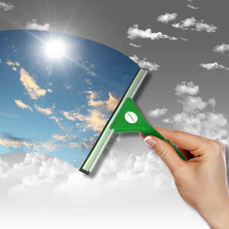 Hand cleaning window with blue sky and white clouds