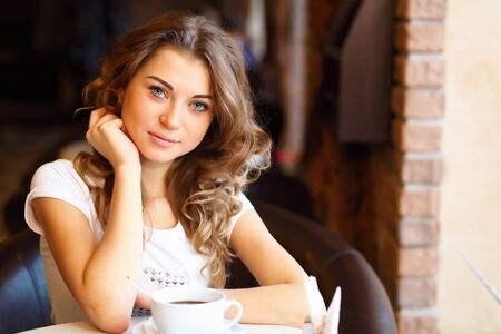 Portrait of young pretty woman sitting in restaurantの写真素材