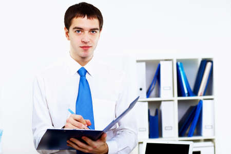 Young smiling happy businessman at work in officeの写真素材