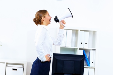 Young woman in business wear with megaphone in officeの写真素材