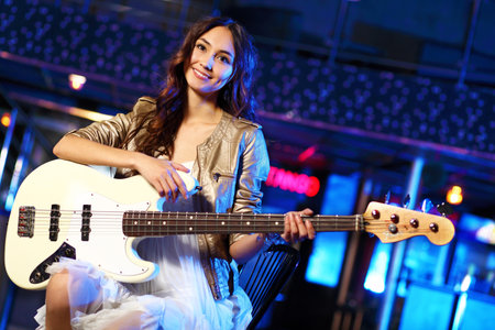 Young guitar player with instrument performing in night club
