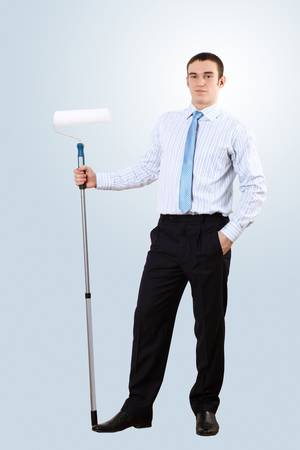 Young businessman standing against blank wall with brushの写真素材