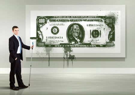Young man with paint brush and banknote painted on the wallの写真素材