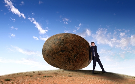 Image of businessman rolling a giant stoneの写真素材