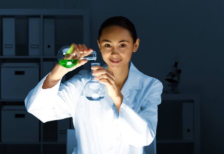 Young chemist in white uniform working in laboratoryの写真素材