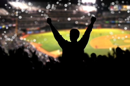 Image of a full stadium with silhouettes of fan on the foregroundの写真素材