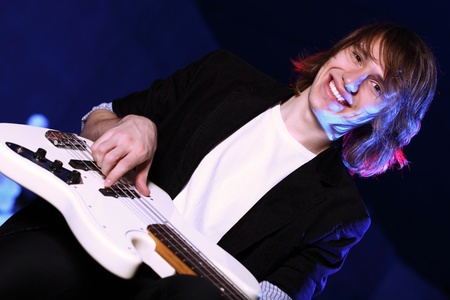 Young guitar player with instrument performing in night clubの写真素材